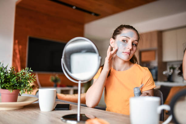 istock Beautiful Female Applying Face Skin Mask While Looking At Mirror Reflection For Precision 1327660826