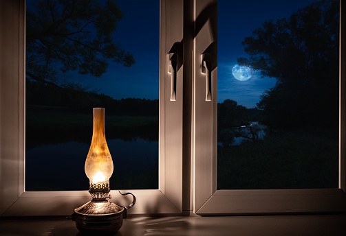 night landscape outside the window moonlight burning kerosene lamp on the windowsill