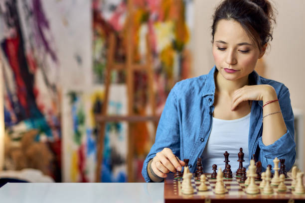 istock Young woman making chess move while sitting at home and playing chess alone 1327671152