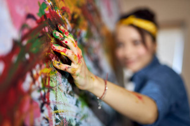 istock Female painter applying paint on canvas with fingers while creating a large modern abstract oil painting 1327671263
