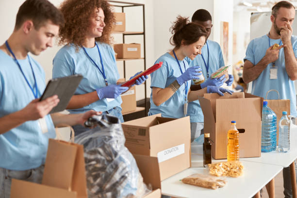istock Diverse people in protective gloves sorting, packing foodstuff in cardboard boxes, volunteering together in community, working on donation project 1327672102