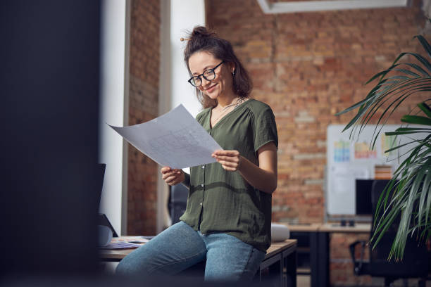 istock Busy interior designer or architect wearing glasses working on a blueprint for new project, leaning on the table in her office 1327672141