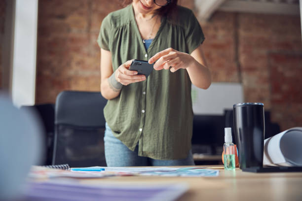 istock Creative woman, interior designer or architect texting or taking picture of a blueprint using smartphone, working on new project, standing in her office. Focus on phone 1327672150