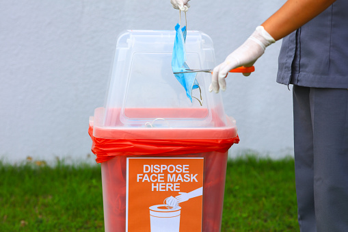 new normal, hand cut used facemask by scissors before dispose in to red binScarp or disposed Hygienic mask in red bin
