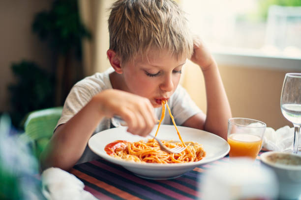istock Cute little boy eating spaghetti 1327676646
