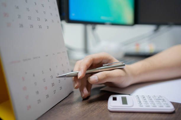 istock close up on employee man hand using pen pointing schedule (timetable) on calendar to writing list of work and make appointment meeting at desk for life balance concept 1327677713