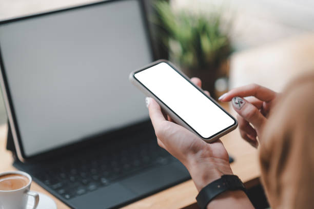 istock Businesswoman using mobile phone on wooden table. Blank white screen. Mock up. 1327677797