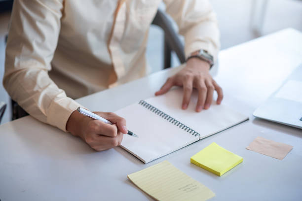 istock Image of a man taking notes in a notebook using a pen at the office. 1327677843