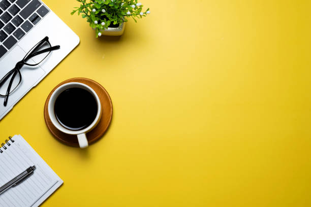 istock Top view of yellow workspace with coffee keyboard, glasses, copy space. 1327677845