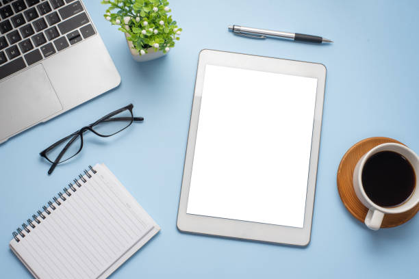 istock Workspace tablet blank white screen and working equipment on a blue background. Mock up. 1327677927