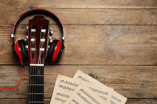 Composition with guitar and music notations on wooden table, flat lay. Space for text