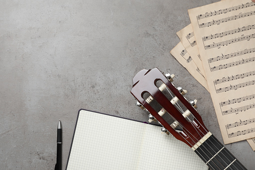 Composition with guitar and music notations on grey table, flat lay. Space for text