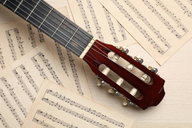 istock Composition with guitar and music notations on light wooden table, flat lay 1327679312