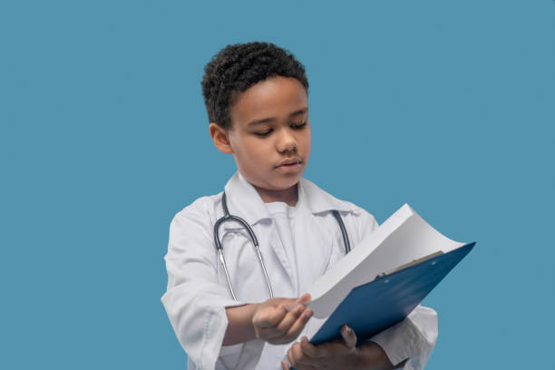 istock African american boy in lab coat with folder 1327679902