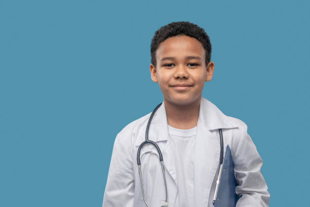 istock Friendly smiling boy in lab coat and stethoscope 1327679920
