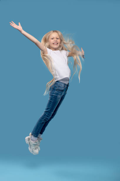 istock Girl jumping upwards with her hands to sides 1327679946
