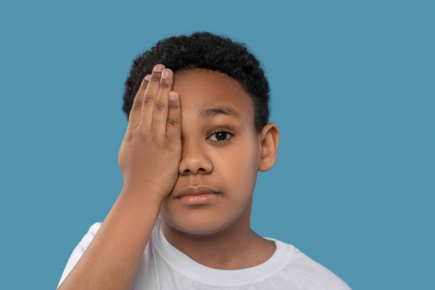 istock Boy covering one eye with his palm 1327679982