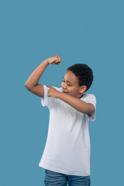 istock Boy rejoicing in his strong muscles 1327680032