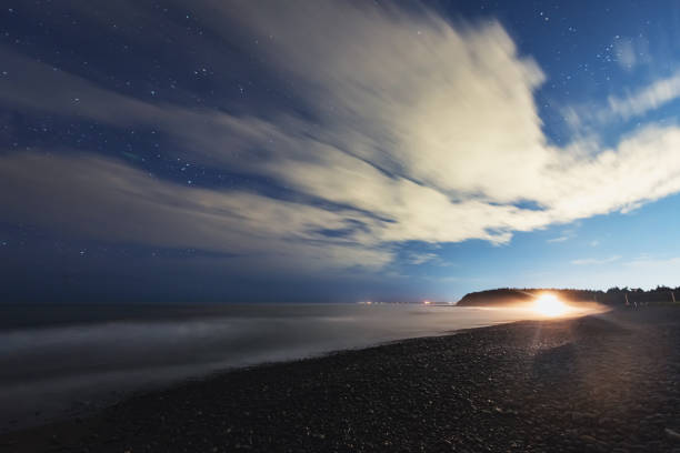 A wide view of a Nova Scotian beach illuminated by a distant car's headlights.