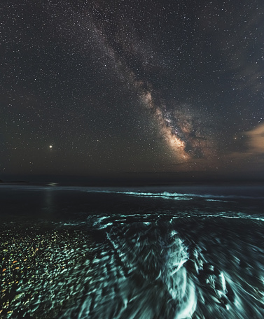 The Summer Milky Way shines over the Atlantic coastline of Nova Scotia. Long exposure with light painting.