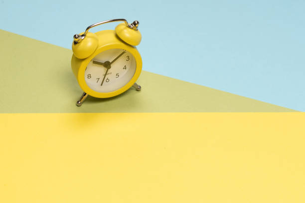 istock Yellow alarm clock on a yellow, blue and green background. Time concept. 1327682992