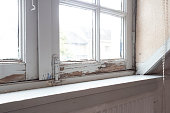 istock Old wooden window frames with rotting wood and cracked peeling paint, house needs renovation and new frames 1327683208