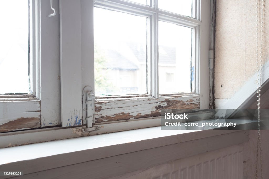 Old wooden window frames with rotting wood and cracked peeling paint, house needs renovation and new frames Old wooden window frames with rotting wood and cracked peeling paint, house needs renovation and new frames closeup Window Stock Photo