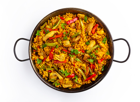 Chicken paella on white background, a traditional Valencian (Spanish) dish made of rice with chicken and vegetables in a pan. view from above, flat lay