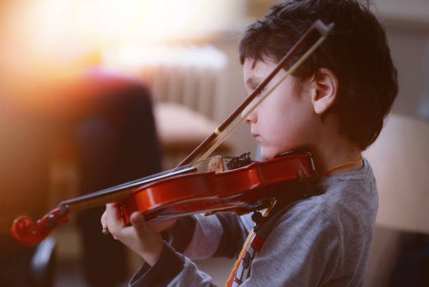istock Child playing the violin in  room 1327685465