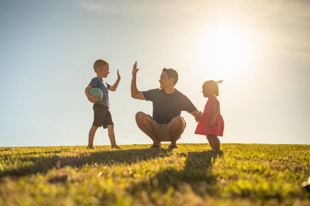 Father, son and daughter playing together outdoors. stock photo