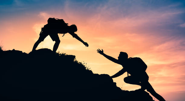 мужчина-турист помогает своему другу достичь вершины. - rock human hand human arm climbing стоковые фото и изображения