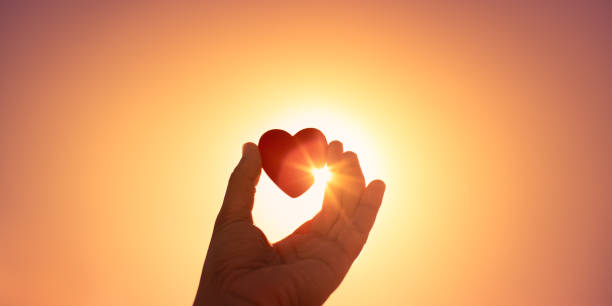 istock Hand holding heart at sunset. 1327685979