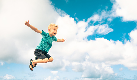 Happy 4 year old boy jumping in the air. Happiness concept.