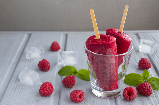 Close-up on popsicles with  raspberry in the drinking glass on the gray background