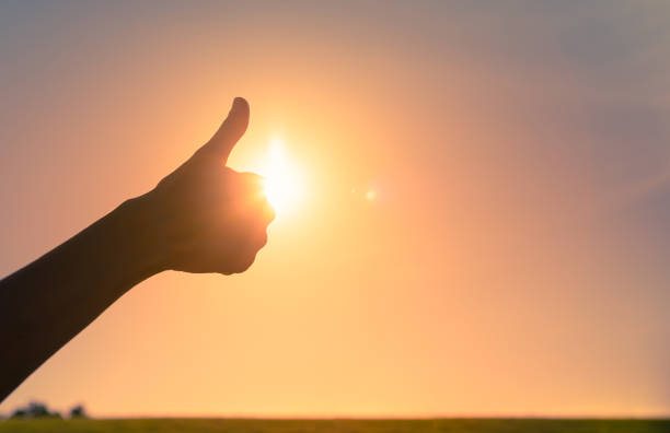istock Man showing thumbs up against a sunset sky. 1327687020