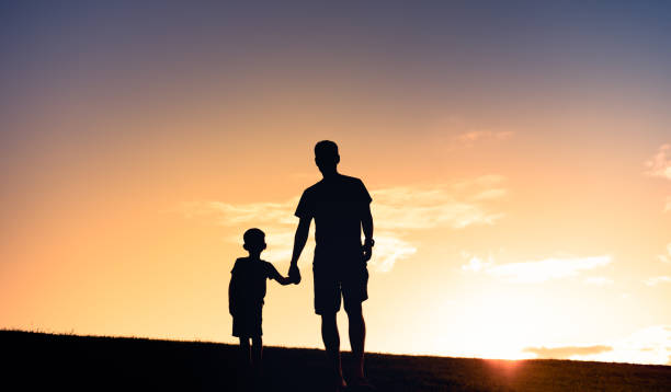 Father and son watching beautiful sunset. stock photo