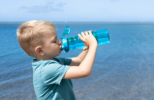 Little boy drinking water from bottle. Hydration, health concept. Drinking water is important.
