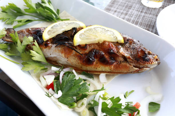 istock Fried trout with onions and herbs on plate 1327688189
