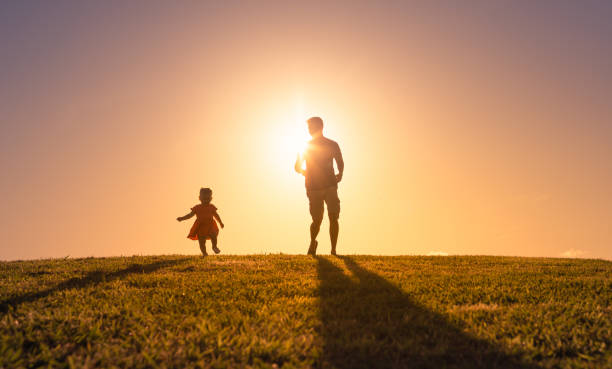 istock Father and daughter in park at sunset 1327688281