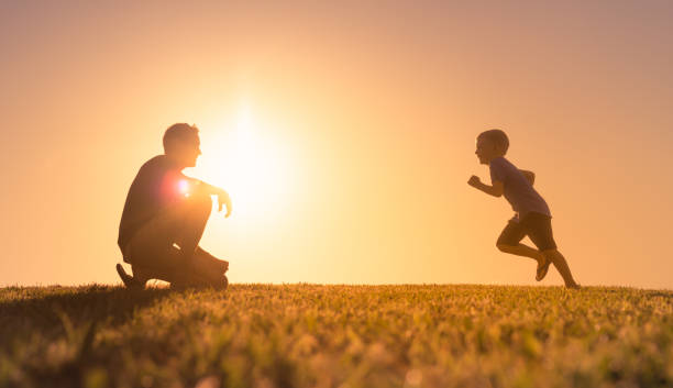 padre che gioca con suo figlio nel parco. - figlio maschio foto e immagini stock