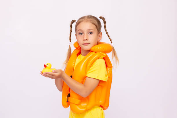 giovane ragazza con giubbotto di salvataggio giallo e un'anatra di gomma su sfondo bianco. - life jacket isolated red safety foto e immagini stock