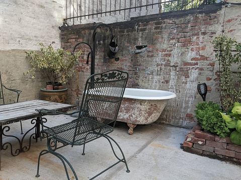outdoor dining space in vintage looking style with plants and rusted tub against brick wall