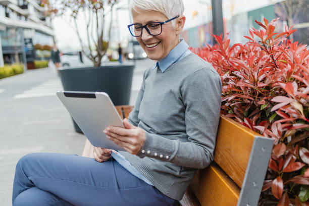istock Senior woman is using digital tablet on the bench 1327694631