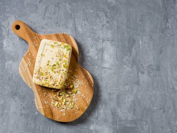 istock Sesame halva with pistachios on a teak chopping board on a grey background. Top view. Copy space. 1327695591