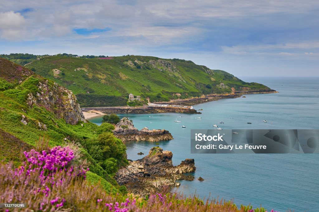 Bouley Bay Image of Bouley Bay fromadjacent cliff paths. with cloudy sky and calm sea. Jersey, Channel Islands Channel Islands - England Stock Photo