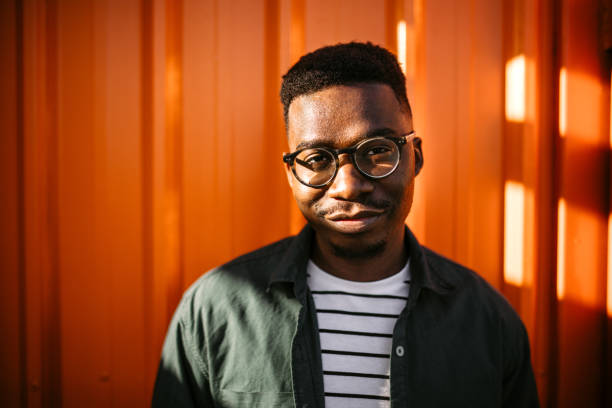 Young, cheerful black man leaning on orange door background