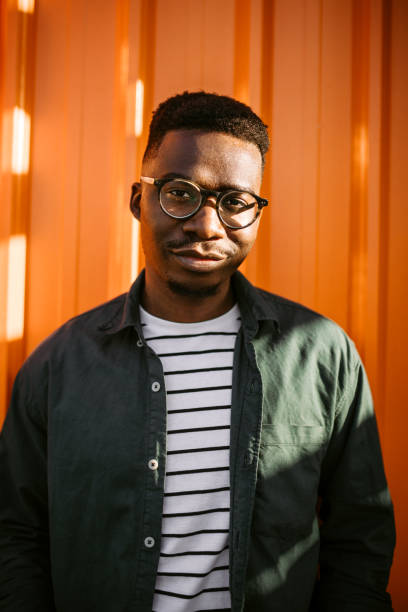 istock Young, cheerful black man leaning on orange door background 1327702587