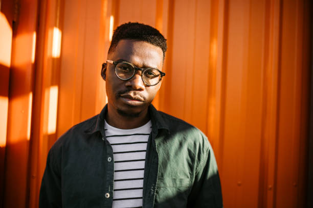 istock Young, cheerful black man leaning on orange door background 1327702594