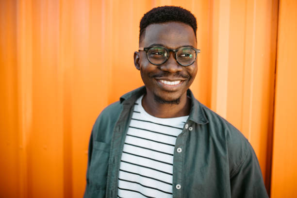 istock Young, cheerful black man leaning on orange door background 1327702603
