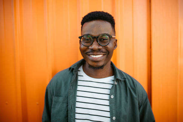 istock Young, cheerful black man leaning on orange door background 1327702618
